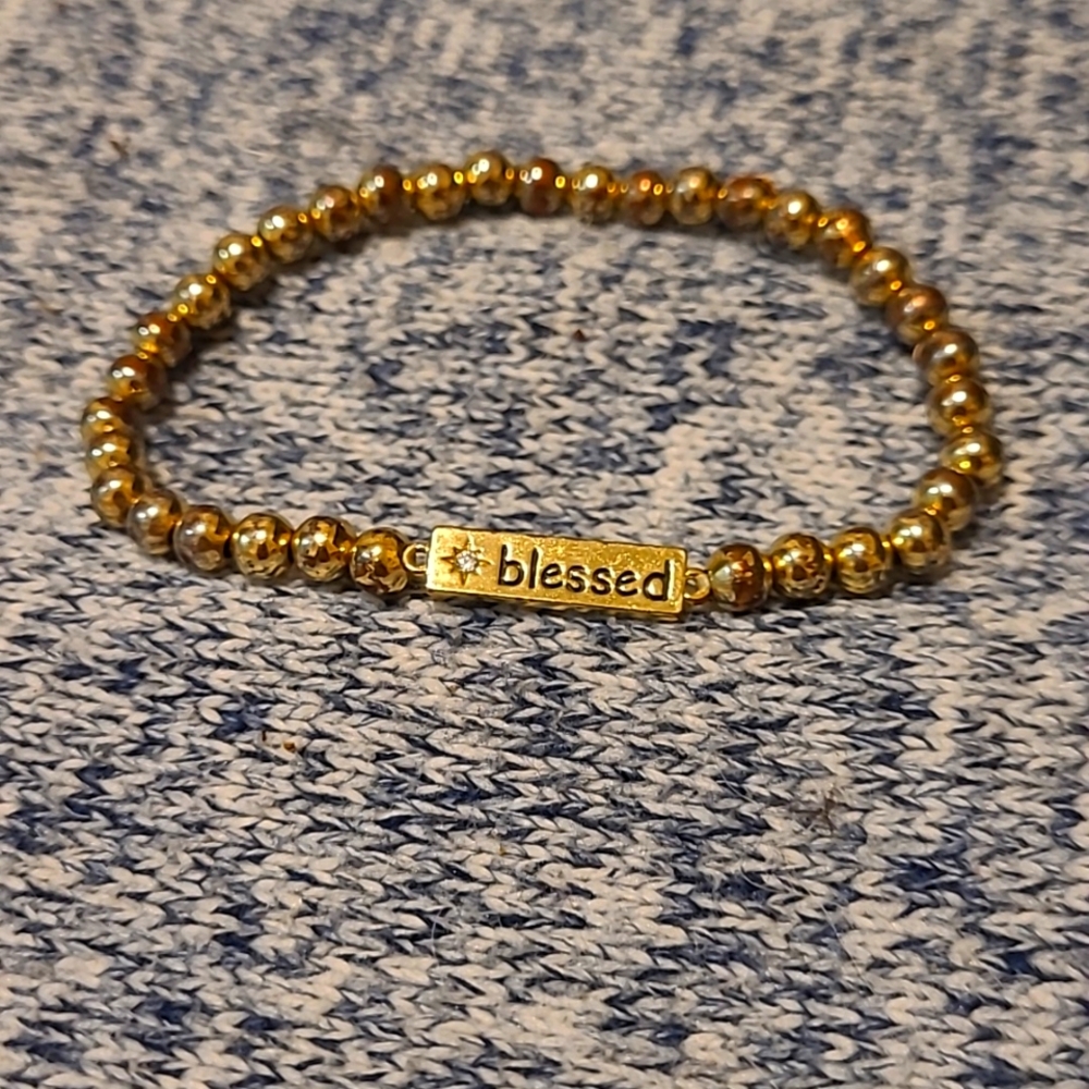 A yellow gold bracelet that says blessed